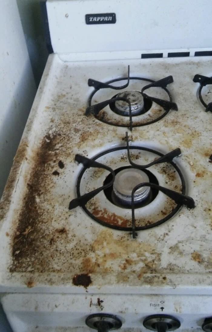 Gas stovetop covered in grease and burnt food before cleaning